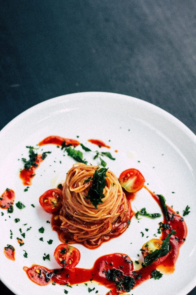 Plate of spaghetti with tomato sauce and garnished with fresh tomatoes and herbs.