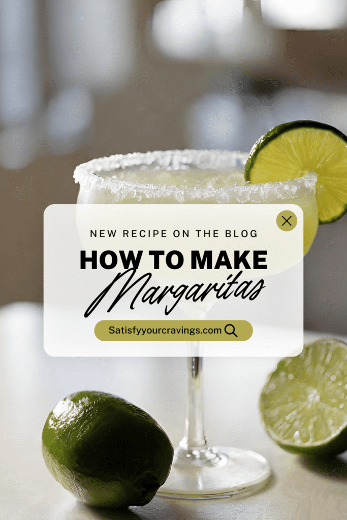 A freshly prepared classic Margarita cocktail with a salted rim, garnished with a lime wheel, displayed on a table alongside two halves of a freshly cut lime.