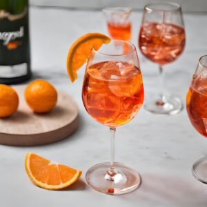 Glass of Aperol Spritz cocktail with orange slice garnish on a wooden table