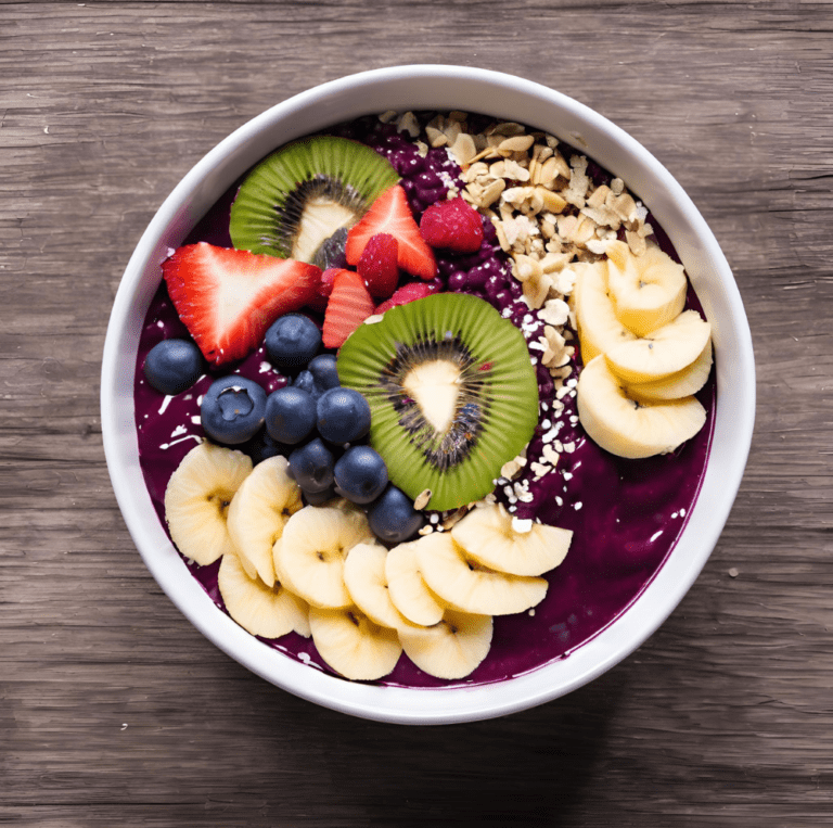 A vibrant acai bowl topped with fresh slices of kiwi, strawberries, blueberries, raspberries, banana, and a sprinkle of granola, served in a white bowl on a wooden surface.