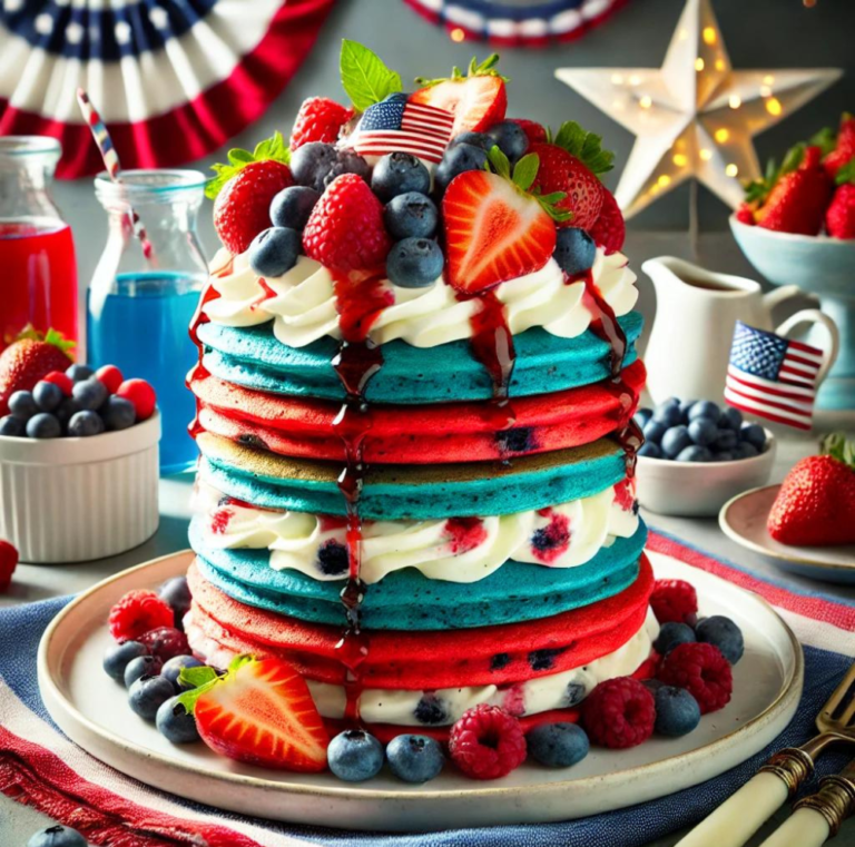 A tall stack of red, white, and blue pancakes with whipped cream, fresh berries, and syrup drizzle.