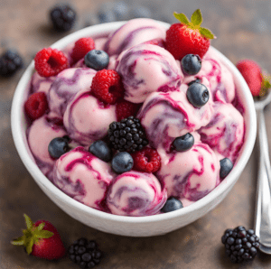 A bowl of berry swirl frozen yogurt topped with fresh strawberries, raspberries, blackberries, and blueberries.