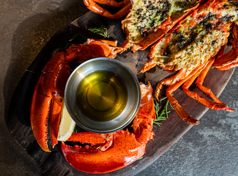 Grilled lobster tails with garlic herb butter served on a wooden board with a bowl of melted butter, perfect for summer BBQs and gourmet seafood lovers.