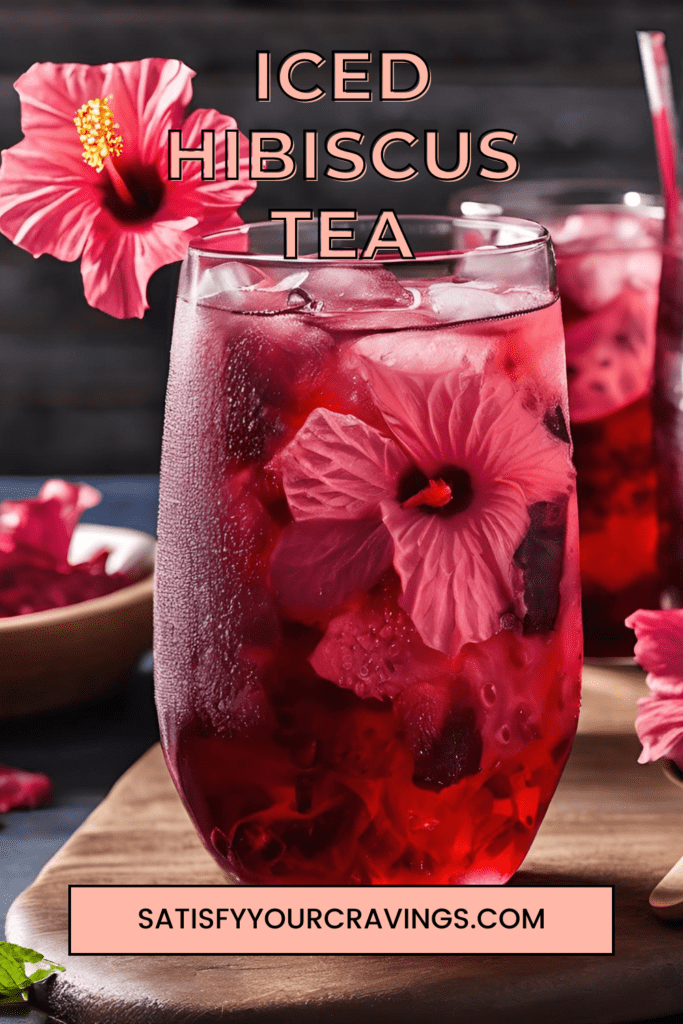 A close-up view of a glass of iced hibiscus tea garnished with fresh hibiscus flowers and ice cubes, set on a wooden table with a bowl of dried hibiscus flowers in the background.