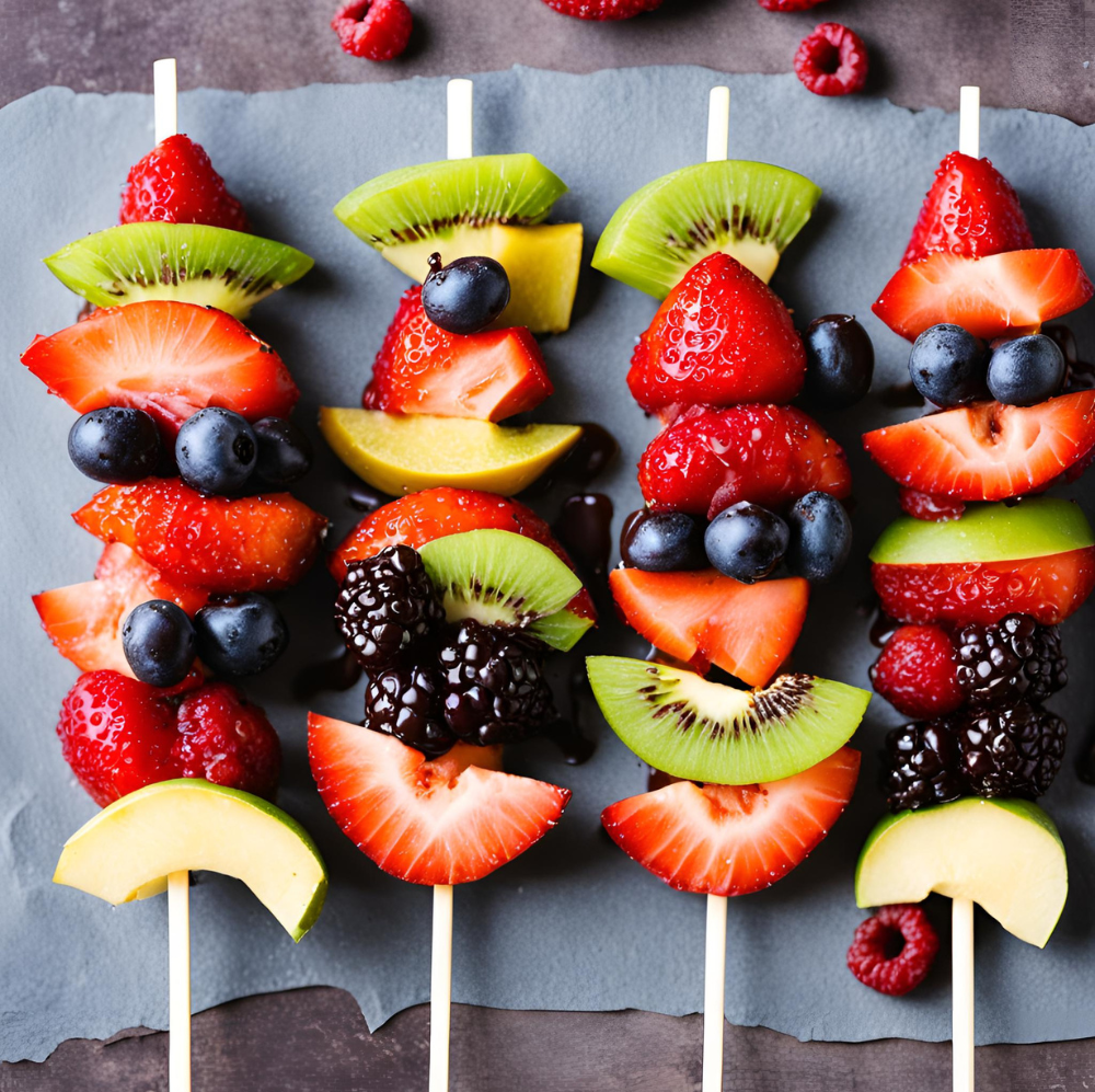 Four fruit kebabs featuring strawberries, kiwi, blackberries, blueberries, and avocado slices on a slate board.