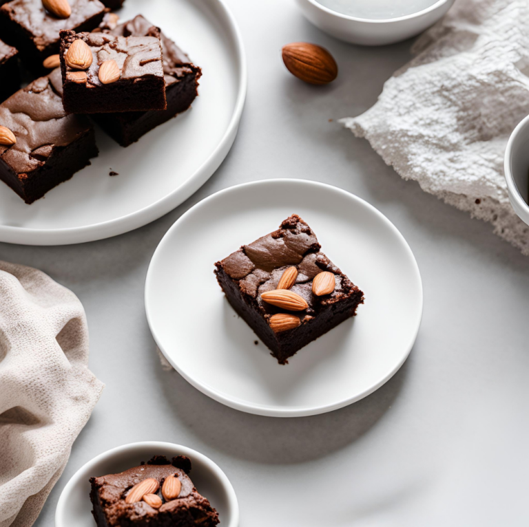 Overhead view of almond flour brownies served on white plates with almond garnishes and a minimalist style.